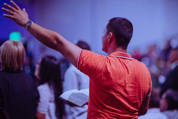 man at a prayer service with his arm up